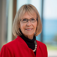 Margaret Leinen in red jacket with Scripps pier and ocean in the background